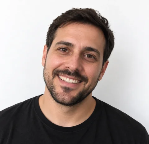 AI-generated photo of a man with a beard tilting his head to one side and smiling widely with his teeth showing, in front of a white wall